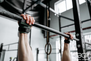 The man is doing exercises on the parallel bars using lifting grips