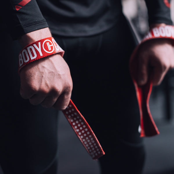 Man puts on Red Weight Lifting Wrist Straps V1 to lift the barbell
