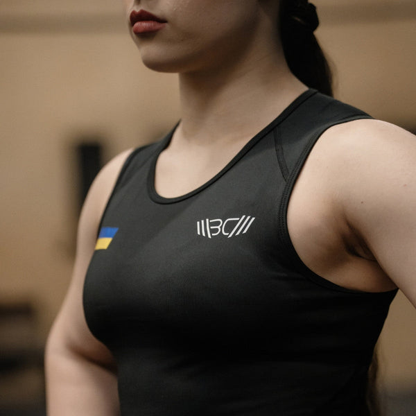 Woman in WOMEN'S WEIGHTLIFTING COMPRESSION SINGLET S-4 standing in a gym (close-up view) - Warm Body Cold Mind