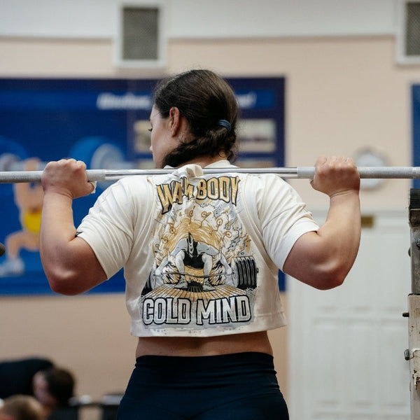 Person lifting a barbell in a gym wearing a beige Women's Cropped T-shirt - Lift Off  - Warm Body Cold Mind